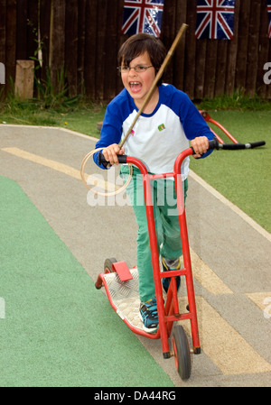 7 ans bénéficiant à un scooter ride summer fete, feuille, Hampshire, Royaume-Uni. Banque D'Images