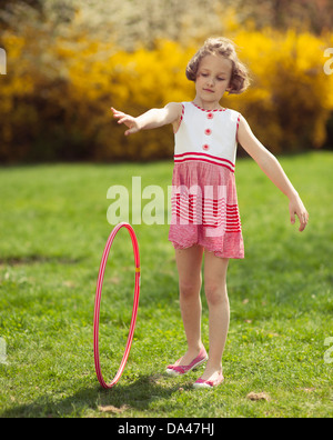 Jeune fille rolling hula hoop in park Banque D'Images