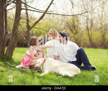 Family sitting in park with dog Banque D'Images