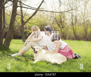 Family sitting in park with dog Banque D'Images