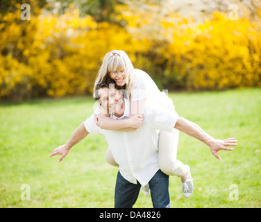 Man piggybacking woman in park Banque D'Images