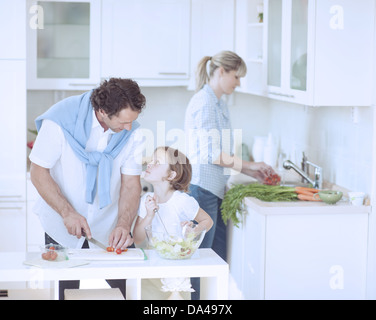 Père et fille à l'un l'autre tout en préparant des repas sains dans la cuisine Banque D'Images