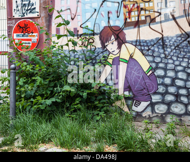 Street art - peinture de fille sur le mur avec les mauvaises herbes en premier plan Banque D'Images