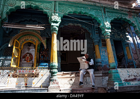 Man reading newspaper et assis en face d'un temple. Jodhpur, Rajasthan, India Banque D'Images