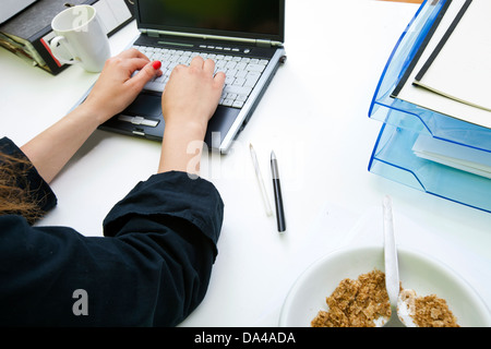 Close up of womans hands typing on laptop avec dossiers et mug Banque D'Images