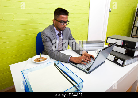 Portrait d'homme d'affaires indien travaille sur son ordinateur portable à son bureau. Banque D'Images