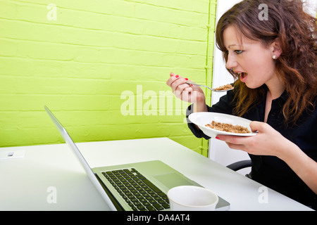 Close up of woman eating at her desk Banque D'Images