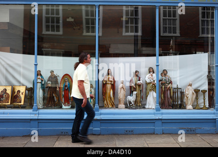 Statues religieuses en exposition dans une vitrine comme un homme marche passé. Banque D'Images