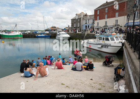 Les gens se détendre au soleil sur la cale du port de Padstow Cornwall UK Banque D'Images