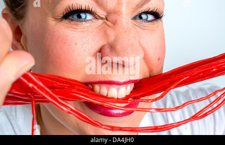 Une jeune femme de manger beaucoup de bonbons réglisse rouge dentelle Banque D'Images