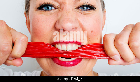 Une jeune femme de manger beaucoup de bonbons réglisse rouge dentelle Banque D'Images