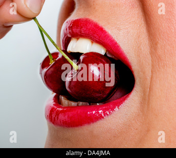 A woman eating cerise rouge, Close up Banque D'Images