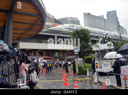 Tokyo, Japon. 4 juillet 2013. Un train rapide, le train de voyageurs à grande vitesse, zips les frais généraux en Shintaro Ishihara, co-leader du parti de la restauration du Japon, fait son premier discours au lancement du Tokyo Yurakucho railroad station comme faisant campagne pour l'élection de la chambre haute triennale, prévue pour le 21 juillet, commence le jeudi 4 juillet 2013. La moitié des 242 sièges de la Chambre des Conseillers du régime alimentaire sont en jeu tous les trois ans sous une combinaison de circonscriptions et la représentation proportionnelle. Autour de 430 candidats en lice pour les 121 sièges à pourvoir. (Photo de Natsuki Sakai/AFLO/Alamy Live New Banque D'Images