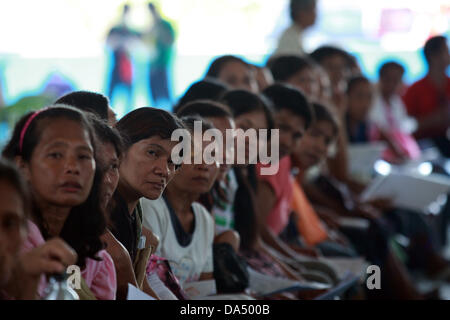 GENERAL SANTOS, Philippines, 4 juillet 2013. Les résidents de la partie sud de la ville de General Santos Philippine pour attendre leur tour pour recevoir une subvention du gouvernement, le 4 juillet 2013. Sous programme de transfert d'argent conditionnel mis en œuvre par le ministère des Affaires sociales et du développement, le gouvernement fournit des subventions mensuelles aux familles pauvres. Les bénéficiaires sont tenus d'envoyer leurs enfants à l'école publique, et d'avoir les enfants et les mères se rendent régulièrement dans des centres de santé publique. Maitem Crédit : Jeoffrey/Alamy Live News Banque D'Images