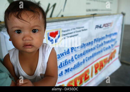 GENERAL SANTOS, Philippines, 4 juillet 2013. Un enfant dans le sud de la ville de General Santos, Philippines est vu au cours de leur octroyer la mise en liberté le 4 juillet 2013. Sous programme de transfert d'argent conditionnel mis en œuvre par le ministère des Affaires sociales et du développement, le gouvernement fournit des subventions mensuelles aux familles pauvres. Les bénéficiaires sont tenus d'envoyer leurs enfants à l'école publique, et d'avoir les enfants et les mères se rendent régulièrement dans des centres de santé publique. Maitem Crédit : Jeoffrey/Alamy Live News Banque D'Images