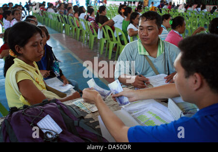 GENERAL SANTOS, Philippines, 4 juillet 2013. Un résident dans le sud de la ville de General Santos, Philippines financier reçoit des subventions du gouvernement, le 4 juillet 2013. Sous programme de transfert d'argent conditionnel mis en œuvre par le ministère des Affaires sociales et du développement, le gouvernement fournit des subventions mensuelles aux familles pauvres. Les bénéficiaires sont tenus d'envoyer leurs enfants à l'école publique, et d'avoir les enfants et les mères se rendent régulièrement dans des centres de santé publique. Maitem Crédit : Jeoffrey/Alamy Live News Banque D'Images