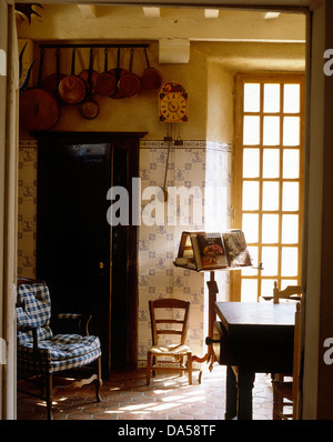 Vue à travers la porte ouverte à l'anglais pays salle à manger avec mur carrelé blanc +bleu et un fauteuil avec coussins bleu vérifié Banque D'Images