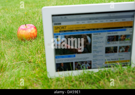 IPad sur l'herbe, avec une pomme à côté de lui, affichant le site web de la BBC, sports section service de mise à jour à Wimbledon Banque D'Images