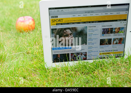 IPad sur l'herbe, avec une pomme à côté de lui, affichant le site web de la BBC, sports section service de mise à jour à Wimbledon Banque D'Images