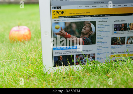 IPad sur l'herbe, avec une pomme à côté de lui, affichant le site web de la BBC, sports section service de mise à jour à Wimbledon Banque D'Images