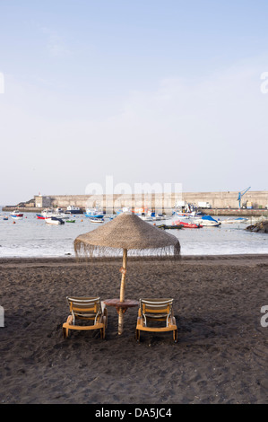 Ratten chaises longues et parasol sur la plage à Playa San Juan, Tenerife, Canaries, Espagne Banque D'Images