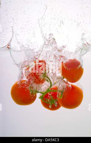 Les tomates dans l'eau éclaboussée Banque D'Images