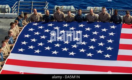 Les Marines américains et les marins tenir le drapeau américain pour commémorer le jour de l'indépendance dans le poste de pilotage de l'USS Kearsarge 4 juillet 2013 dans la mer Rouge. Banque D'Images