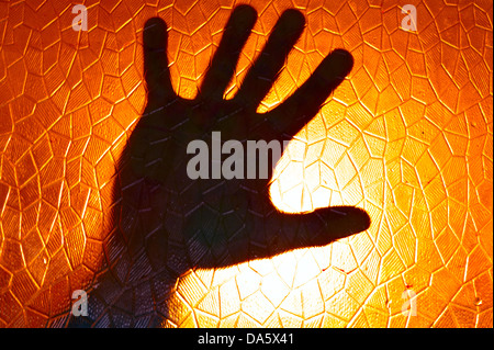 Silhouette à la main sur fond de couleur orange feu vitrail avec motif géométrique cinématique d'Horreur Banque D'Images