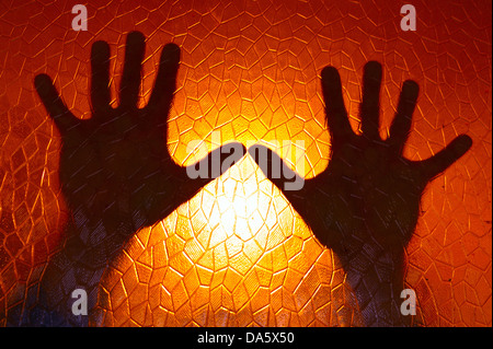 Mains Silhouette sur fond de couleur orange feu vitrail avec motif géométrique cinématique d'Horreur Banque D'Images