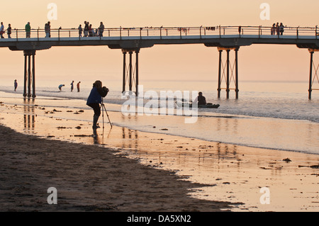 Ciel coucher de soleil d'été colorés et voir des gens marcher sur la jetée en bord de mer à la pagaie, photographe & photo - Sawai madhopur, England, UK. Banque D'Images