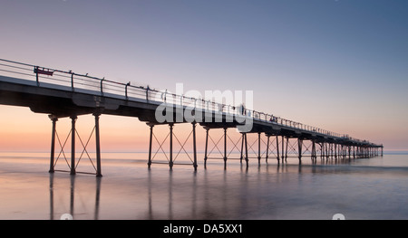 En vertu de l'été haut en couleurs, de ciel coucher de soleil Vue de la plage de sable de personnes marchant sur la jetée en bord de mer historique sur mer calme - Sawai madhopur, England, UK. Banque D'Images