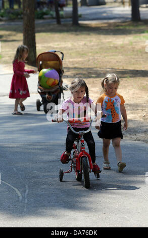 Juillet 05, 2013 - Saint-Pétersbourg, Russie - Enfants s'entraident pour faire du vélo à l'amélioration de la santé 'complexe lumière verte." Le complexe offre des soins de santé, la condition physique, des loisirs et de réhabilitation pour les enfants handicapés et les maladies rares. Les familles nombreuses et les familles monoparentales qui inscrivent leurs enfants à l'un reçu sur l'un des soins. (Crédit Image : © Andreï Pronin/ZUMAPRESS.com) Banque D'Images