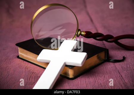 Une bible, croix et loupe. La croix se reflète dans la vitre de la loupe. Banque D'Images