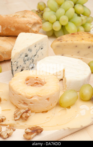 Différents types de fromage et raisins sur planche à découper en bois Banque D'Images