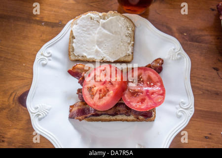 Bacon et tomate sandwich avec mayonnaise assis sur une assiette blanche, sur une table en bois. USA. Banque D'Images