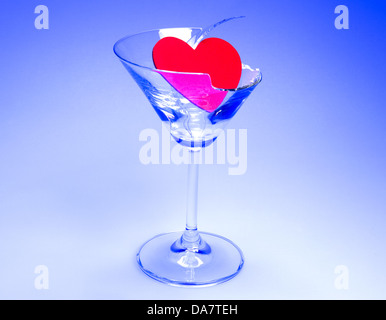 Concept photo de rupture avec coeur brisé assis dans un verre à martini shot sur table lumineuse avec lumière bleue Banque D'Images