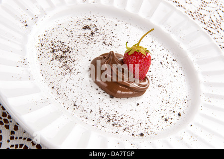 Strawberry assis dans tourbillon de chocolat sur plaque blanche avec spinkles chocolat Banque D'Images