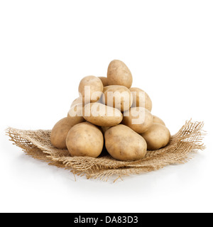 Tas de pommes de terre crues sur tissu du jute, fond blanc Banque D'Images