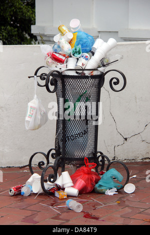 Corbeille publique faite de métal avec beaucoup de déchets dans et hors et sur le plancher. Banque D'Images