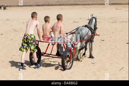 Trois garçons à cheval et piège appréciant les temps chaud sur la plage de Redcar. Banque D'Images