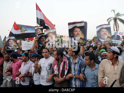 Le Caire, Le Caire, Égypte. 7 juillet, 2013. Les partisans du Président déchu Mohamed Morsi et les frères musulmans membres crier et politiques tiennent des pancartes dans son soutien en tant que ils manifester contre sa chute à Raba al-Adawyia mosquée le 7 juillet 2013, au Caire. La réalisation des photos du président déchu, les islamistes érigé des barricades et établi des postes de contrôle dans toute la capitale, où des dizaines de milliers d'entre eux ont bloqué la route principale de l'aéroport international Crédit : Ahmed Asad APA/Images/ZUMAPRESS.com/Alamy Live News Banque D'Images