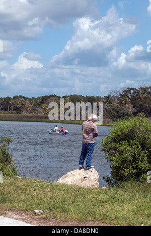 L'homme pêche à pied près de Yankeetown, en Floride. Deux hommes dans un bateau de moteur sont visibles en arrière-plan. Banque D'Images