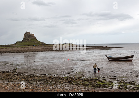 Les touristes visitent le château de Lindisfarne C16th sur Holy Island vu sur la baie avec voile et l'homme et le garçon sur les battures Banque D'Images