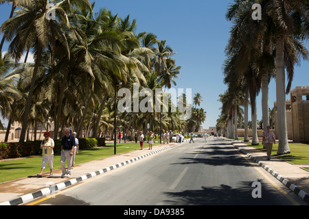 Oman, Dhofar, Salalah, les touristes sur la route bordée de palmiers Sultan Quaboos extérieur bin Said Al Husin du Palais Royal Banque D'Images