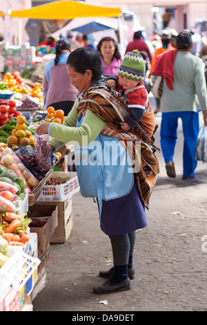 Une mère avec son enfant sur le dos en écharpe au marché hebdomadaire de Pujili, région de l'Equateur Quilotoa Banque D'Images