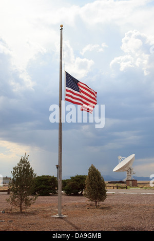 Drapeau américain en berne en premier plan avec une grande antenne satellite en arrière-plan de cette photo au Very Large Array, NM. Banque D'Images