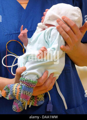 Une infirmière porte bébé Marie soigneusement dans ses bras à l'hôpital pour enfants de Hambourg, Allemagne, le 5 janvier 2011. Un portier a trouvé le bébé nouveau-né abandonné enfermé dans une valise devant le centre des congrès de Hambourg. Les infirmières de l'hôpital pour enfants de babtised 'Marie' le bébé. Le bébé est en bonne santé, la mère, cependant, est encore présente. Photo : Ralf Jakobs Banque D'Images