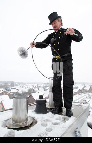 Ramoneur Guenther Gaux présente son uniforme de travail classique sur un toit à Duelmen, Allemagne, 14 décembre 2010. La routine de travail a beaucoup changé pour ramoneurs au cours de la dernière décennie. La disparition des fours à charbon a rendu inutile pour ramoneurs à escalader les toits. Dans l'année de 2010, un ramoneur a trouvé la plupart de ses travaux dans la chaufferie. L'une de ses tâches sans Banque D'Images