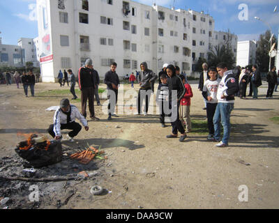 Les tunisiens se rassemblent pour brûler les vêtements d'un homme âgé de 30 ans qui a été abattu par la police dans la nuit avant d'El Khadra, district de Tunis, Tunisie, 16 janvier 2011. Photo : ULRIKE KOLTERMANN Banque D'Images