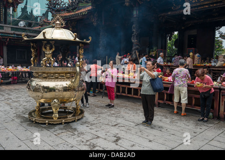 Les fidèles Bouddhistes et Taoïstes d'encens brûlant comme un rituel offrant au Temple Lungshan Mengjia Taipei, Taiwan. Banque D'Images